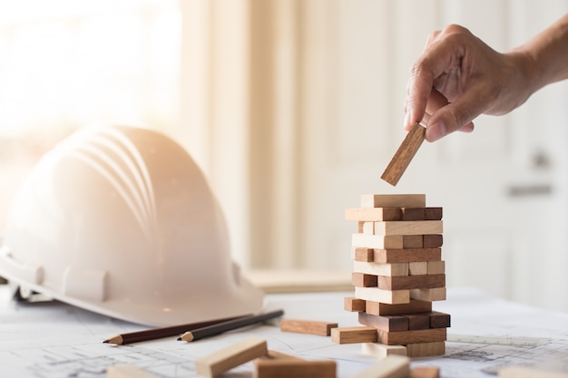 Planung, Risiko und Strategie in der Wirtschaft, Geschäftsmann und Ingenieur Glücksspiel Platzierung Holz Block auf einem Turm.