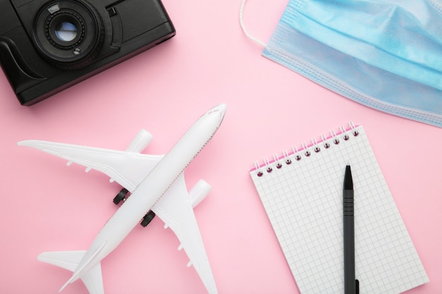 Planung von Sommerferien, Tourismus und Reise Vintage Wand. Reisetagebuch mit Zubehör auf rosa. Flach liegen.