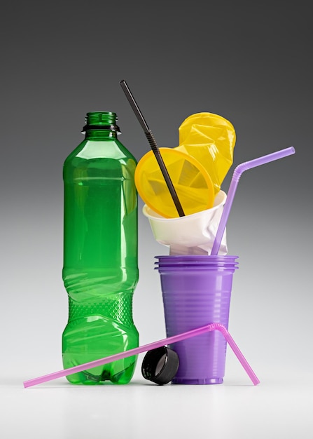 Plástico usado. Vasos desechables, popotes y una botella. El concepto de ecología y reciclaje.