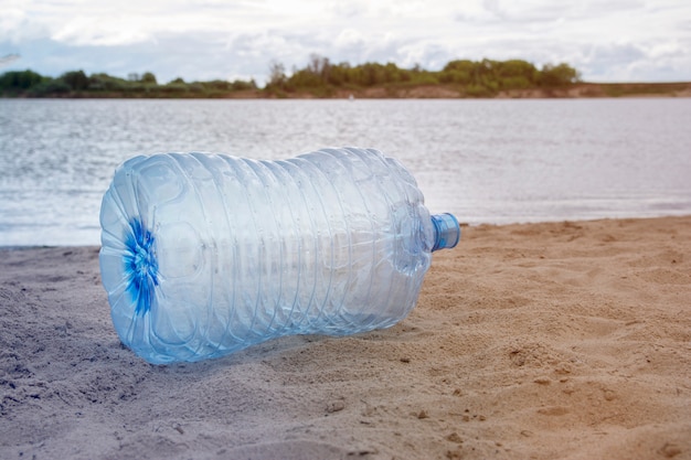 Plastikabfall - Plastikflaschen, die auf dem Sand auf der Flussbank, das Konzept der Wiederverwertung der leeren benutzten Plastikflasche liegen.