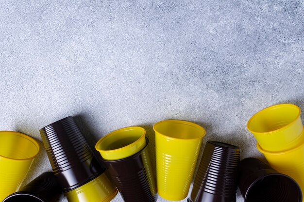 Plastikbecher und -löffel sind über den grauen Hintergrund verstreut