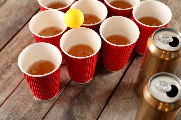 Plastikbier-Pong-Becher und Ball auf Holztisch