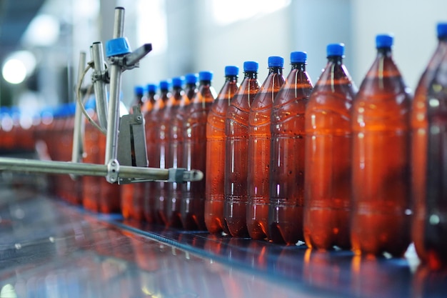 Plastikbierflaschen auf einem Förderband im Hintergrund einer Brauerei