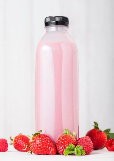 Plastikflasche mit frischem Sommerbeeren-Smoothie auf Holztisch. Erdbeergeschmack.