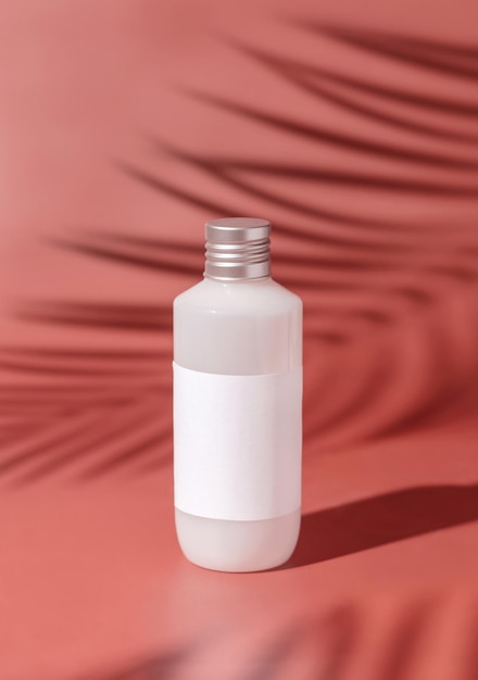 Plastikflasche mit leerem Etikett auf rosafarbenem Palmblatt harte Schatten Mockup