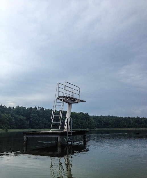 Plataforma de mergulho sobre o lago por árvores contra o céu