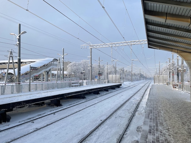 Plataforma ferroviaria vacía sin pasajeros en invierno al atardecer. Ferrocarril, concepto de clima frío