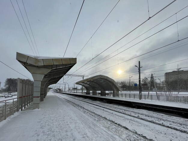 Plataforma ferroviaria vacía sin pasajeros en invierno al atardecer. Ferrocarril, concepto de clima frío