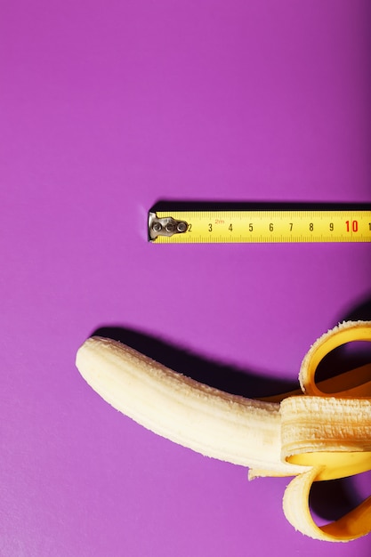 Foto plátano amarillo medido con cinta métrica sobre fondo rosa