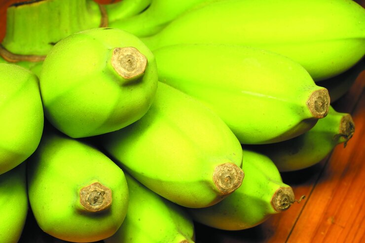 Foto un plátano crudo de gran tamaño de color verde delicioso y beneficioso para el cuerpo colocado en una mesa de madera