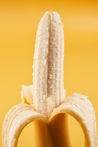 Plátano entero medio pelado aislado en amarillo