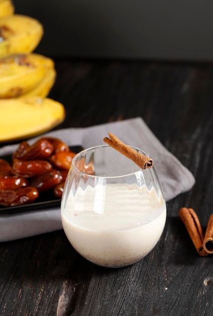 Plátano Fechas Batido de frutas y canela o batido en un vaso sobre una mesa de madera con fondo gris