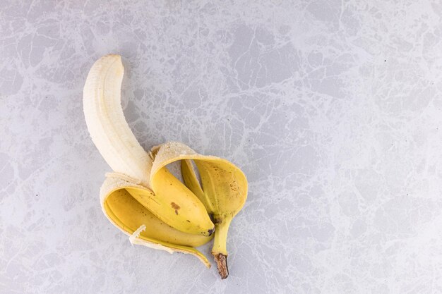 Foto plátano pelado en fondo de mármol blanco concepto de alimentos saludables para uso de fondo