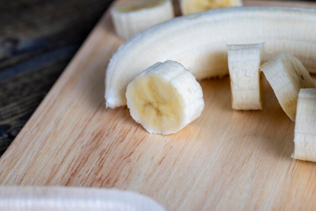 Plátano en rodajas sobre una mesa de madera mientras cocina plátano fresco cortado en varios trozos