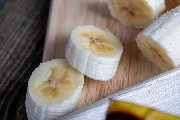 Plátano en rodajas sobre una mesa de madera mientras cocina plátano fresco cortado en varios trozos