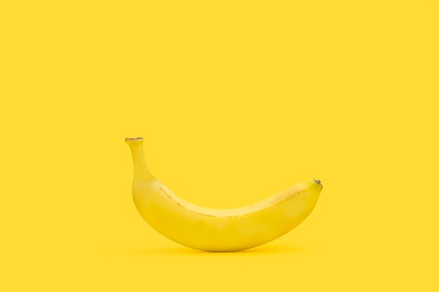 Un plátano sobre un fondo amarillo con espacio de copia
