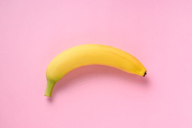 Plátano en superficie rosa.