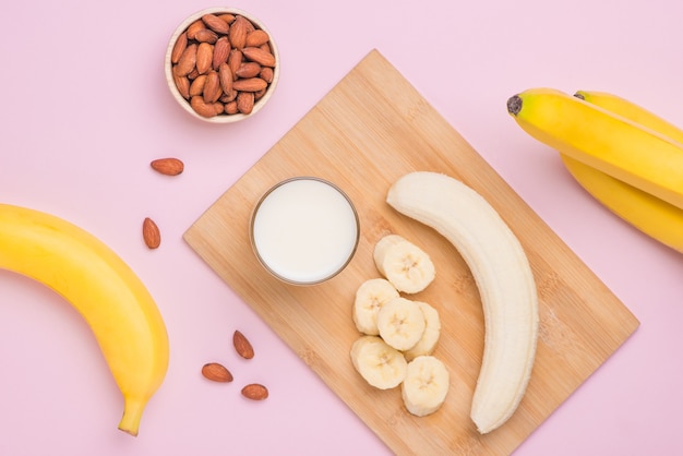 Plátanos con almendras y leche sobre fondo rosa.