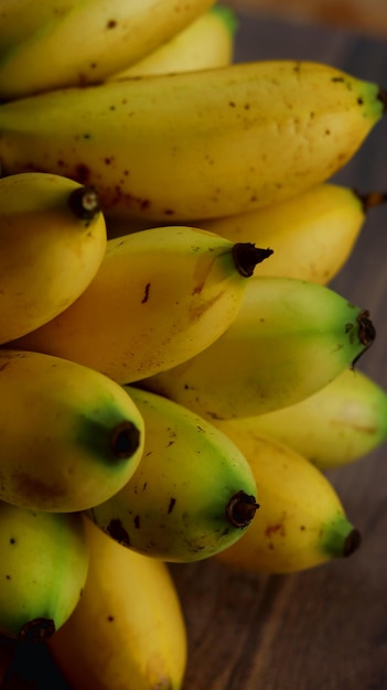 plátanos amarillos maduros agrupados sobre un fondo de madera. Fruta de plátanos pequeños.