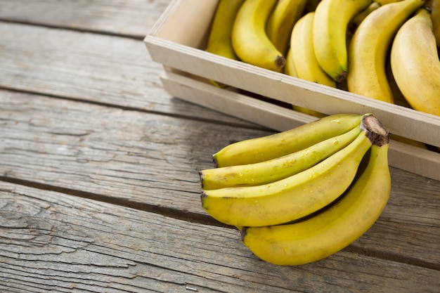 Plátanos en caja de madera sobre mesa de madera