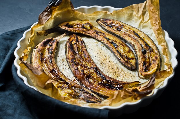 Plátanos fritos con miel en un plato para hornear.