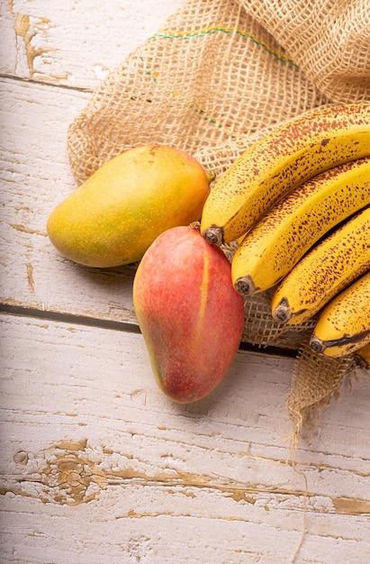 Plátanos maduros y detalles de mangos de un racimo de plátanos muy maduros y algunos mangos enfoque selectivo