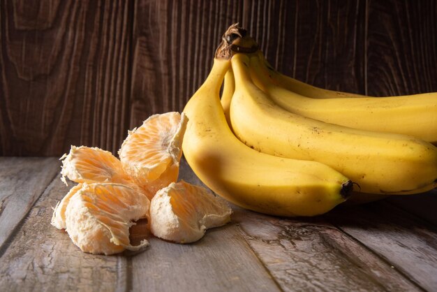 Plátanos y naranjas ponkans fotografiados en enfoque selectivo de madera rústica