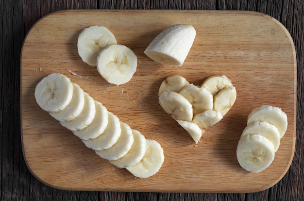 Plátanos en rodajas y forma de corazones en la tabla de cortar de madera