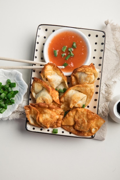 Un plato de albóndigas fritas con cebollas verdes y un plato de salsa