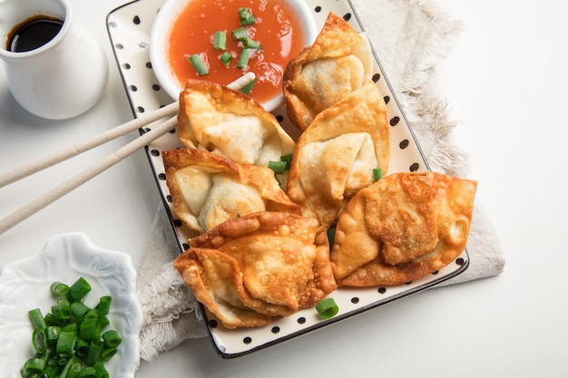 Un plato de albóndigas fritas con un plato de salsa y cebollas verdes al lado.