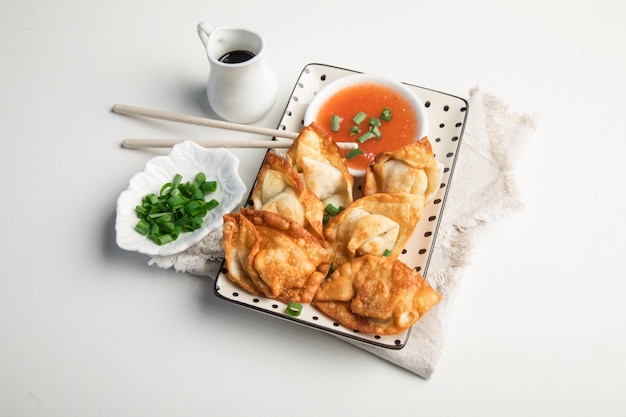 Un plato de albóndigas con un plato de salsa y cebollas verdes.