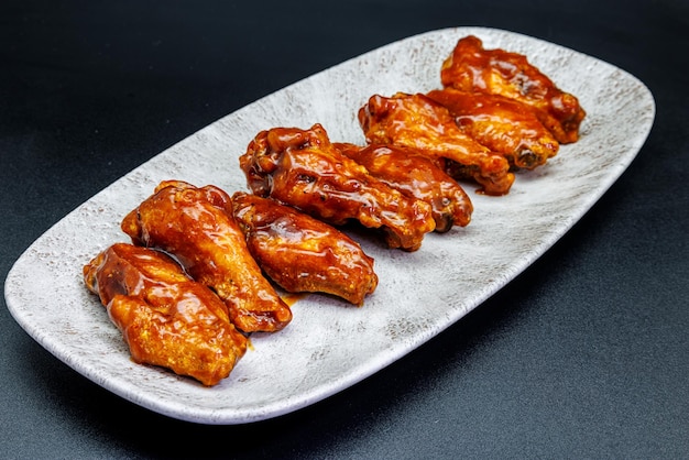 Foto plato de alitas de pollo a la barbacoa sobre fondo negro