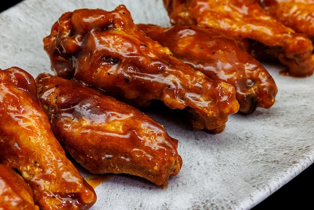 Foto plato de alitas de pollo a la barbacoa sobre fondo negro