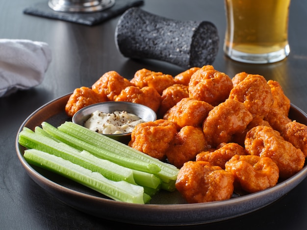 Plato de alitas de pollo deshuesadas con salsa búfalo y palitos de apio