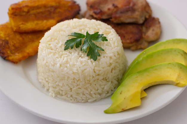 Plato almuerzo dominicano, tostones fritos, arroz blanco acompañados de varios aguacates cortados, comida en casa,