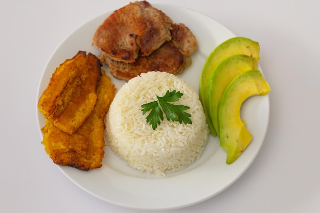 Plato almuerzo dominicano, tostones fritos, arroz blanco acompañados de varios aguacates cortados, comida en casa, toma superior