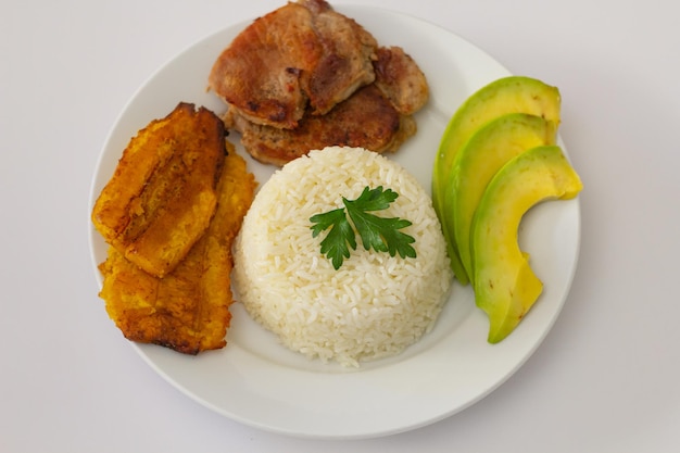 Plato almuerzo dominicano, tostones fritos, arroz blanco acompañados de varios aguacates cortados, comida en casa, toma superior