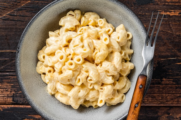 Plato americano Pasta de macarrones con queso y macarrones con queso cheddar. Fondo de madera oscura. Vista superior.