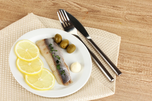 Plato de arenque y limón en un plato sobre una mesa de madera cerrada