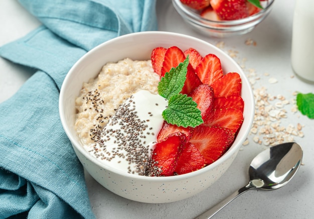 Un plato de avena con fresas, yogur y semillas de chía. Desayuno saludable. Vista lateral, primer plano.