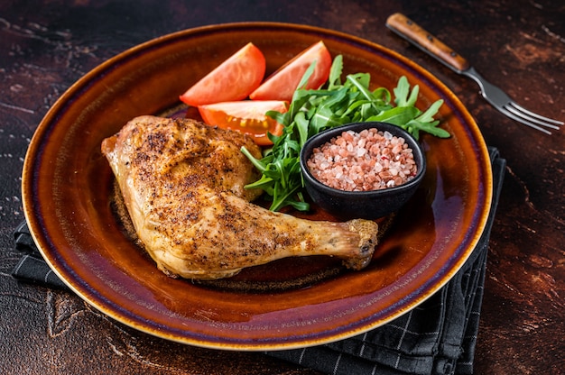 Plato de aves de corral: muslos de pollo asado con ensalada de verduras. Fondo oscuro. Vista superior.