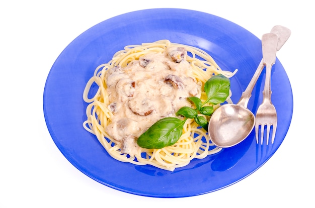 Plato azul con espagueti y salsa de champiñones.