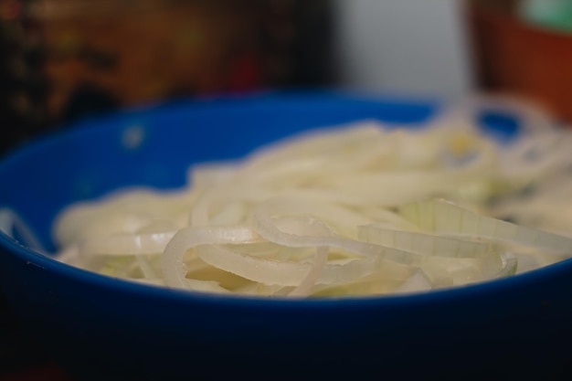 Foto plato azul lleno de cebolla grande en la cocina para preparar un delicioso tamale colombiano