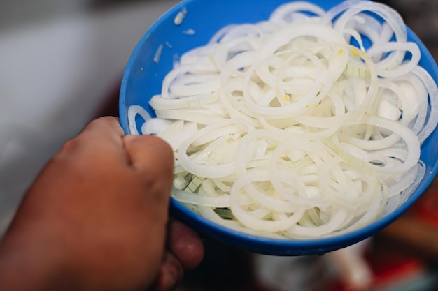 Foto plato azul lleno de cebolla grande en la cocina para preparar un delicioso tamale colombiano