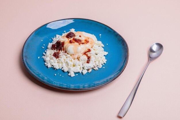 Foto plato azul con queso cottage y mermelada sobre un fondo rosado