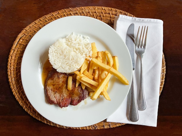 Foto plato de bistec ejecutivo con papas fritas y arroz. comida tradicional brasileña.