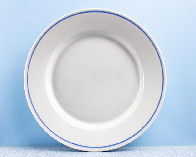 Foto plato blanco antiguo clásico con rayas azules sobre un fondo azul claro primer plano de vajilla de plato vintage