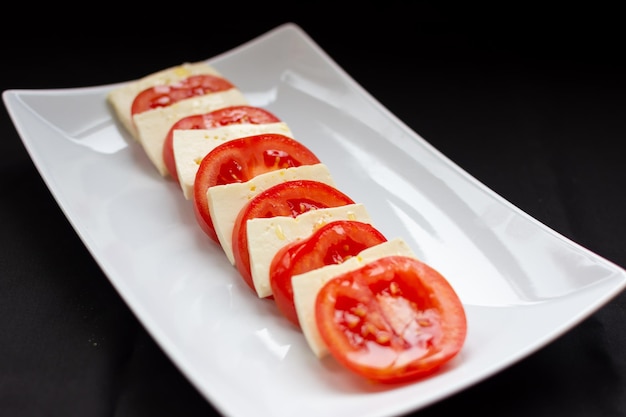 En un plato blanco un aperitivo de tomates y queso.