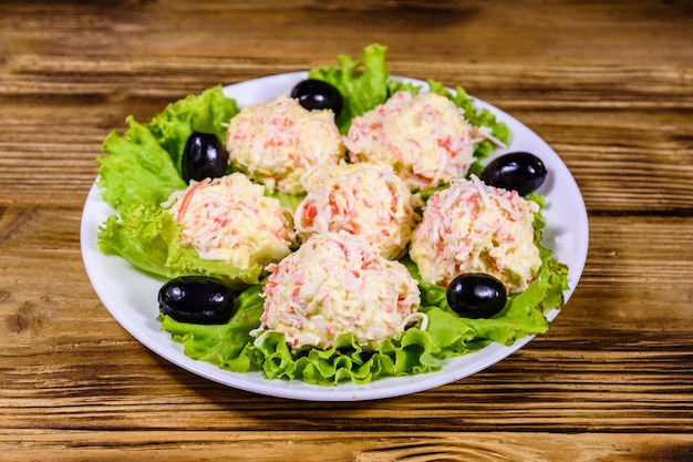 Plato blanco con bolas de cangrejo y hojas de lechuga en la mesa de madera