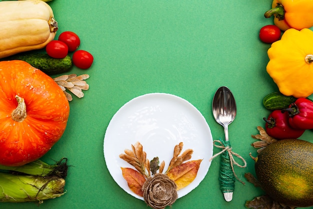 Plato blanco y cubiertos en hojas de otoño y verduras